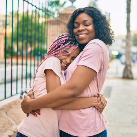 Mother and preteen daughter hugging and smiling