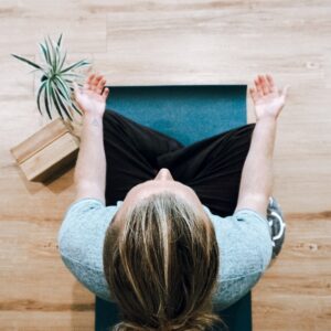Photo taken from above of a woman sitting on a blue yoga mat